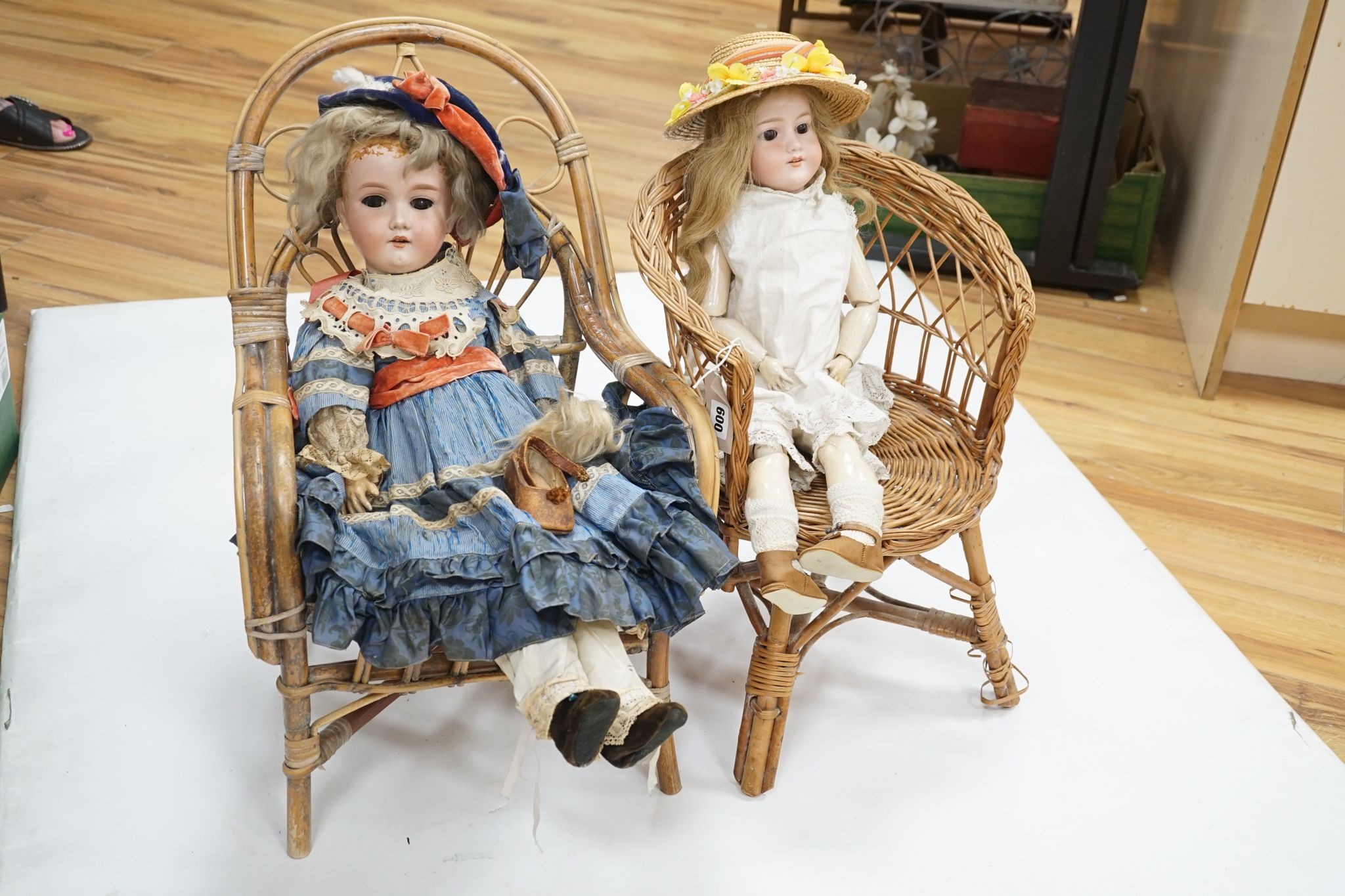 Two Armand Marseille 390 bisque dolls, each in wicker chair